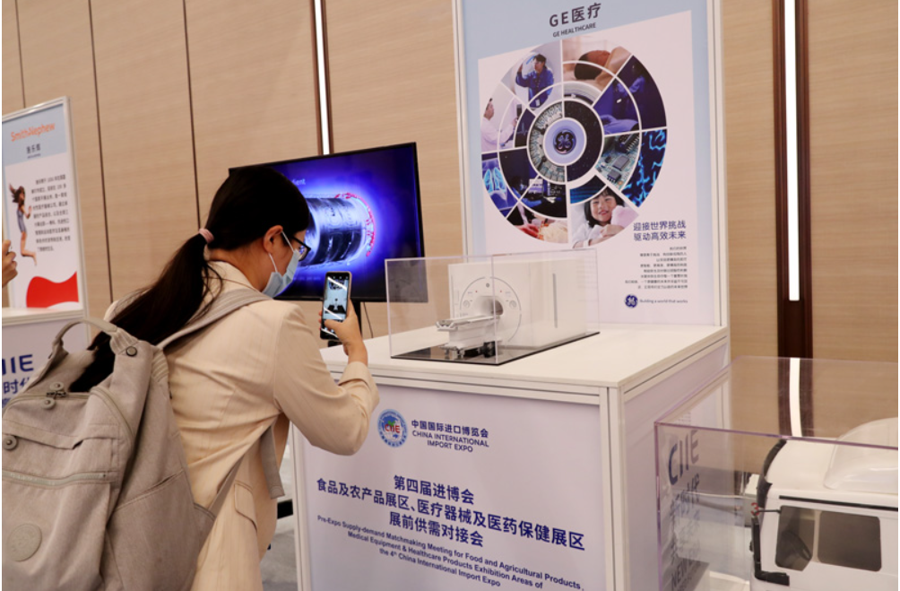 第四屆進博會食品及農產品展區(qū)、醫(yī)療器械及醫(yī)藥保健展區(qū)展前供需對接會的參會嘉賓用手機拍攝參展企業(yè)的展品模型